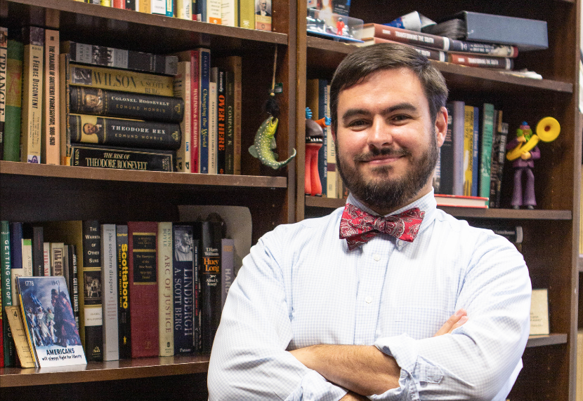 Photo of Downs in front of a full bookcase.
